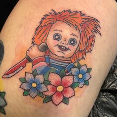 a close up of a tattoo on a person's leg with a knife and flowers