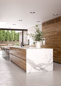 a large kitchen with marble counter tops and wooden cabinetry, along with bar stools