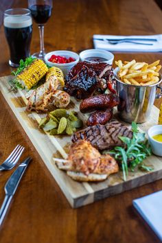 a wooden table topped with different types of food and drinks next to glasses of wine