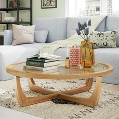 a coffee table with books and vases on it in front of a blue couch