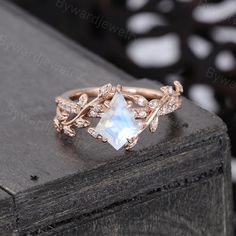 a rose gold ring with an opal stone surrounded by small white diamonds and leaves