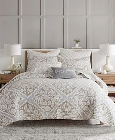 a white and beige bed in a bedroom with two lamps on either side of the bed