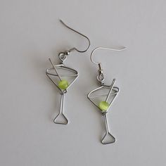 Martini Glass Earrings. Great gift for Bartenders, Hostesses and Waitresses. NOW AVAILABLE IN TWO SIZES. Regular martini glass is 1 1/2 inches high, small martini glass is 1 1/8 inches high (not including earring hooks, see inset photo for scale). Tiny wire martini glasses, complete with green cat's eye bead. Surgical steel hooks are hypo-allergenic. Clear plastic stoppers on backs. Aluminum wire will not tarnish. I have been making custom wire art and jewelry for 30 years. I started in 1989 sel Unique Earring, Wire Earring Designs, Stud Wire Earrings, Earrings Wire, Wire Earring Ideas, Christmas Wire Jewelry, Wired Earrings, Wire Earrings Diy, Wire Jewelry Ideas