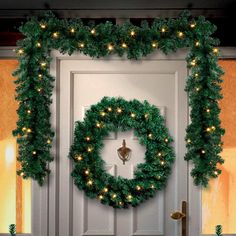 a christmas wreath with lights hanging from it's sides on the front door,