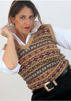 a woman in white shirt and black pants wearing a knitted vest with gold hoop earrings