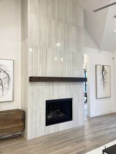 a living room with white walls and wood floors, an open fireplace in the center