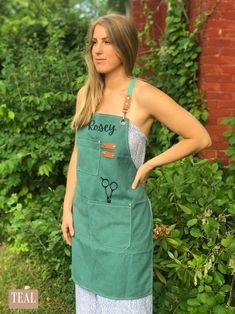 a woman standing in front of some bushes wearing an apron with the word sassy on it