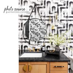 a bathroom with black and white wallpaper, gold faucets and a sink