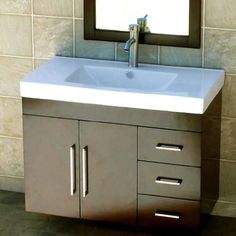 a bathroom sink sitting under a mirror next to a wall mounted faucet in front of a tiled wall