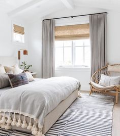 a bedroom with a bed, chair and rug on the floor in front of a window