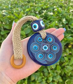 a hand holding a blue ceramic object with eyes on it