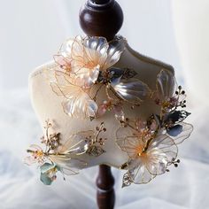 a mannequin with flowers and leaves on it's back end, sitting on a white cloth