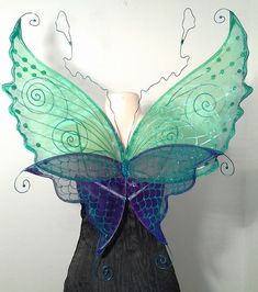 a green and blue butterfly wings on a mannequin headdress with swirls