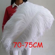 the woman is holding a large white feather on her arm and wearing a red shirt