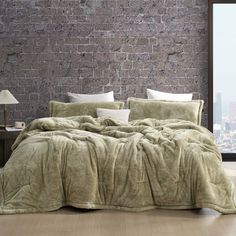 a bedroom with brick wall and wooden flooring is shown in front of the bed