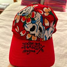 a red hat with a skull and flowers on it sitting on top of a bed