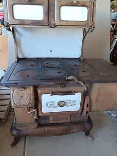 an old fashioned stove with two burners on it in a room filled with other items