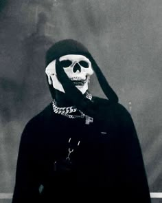 a person in a black outfit with a skull on their face and hands behind his head