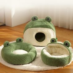 a cat bed with two green frog shaped beds on top of it and a white pillow in the middle