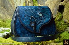 a blue purse sitting on top of a moss covered ground