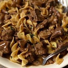 a close up of a plate of food with noodles and beef in sauce on it