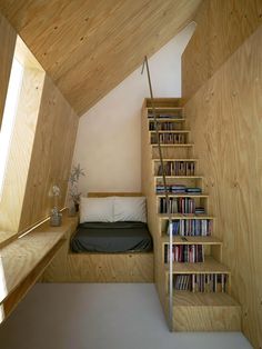 there is a bed and some books on the shelves in this small room with stairs