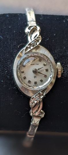 From  ca 1950s, this exquisite 10KT White Gold Lady Hamilton Cocktail Watch defines the glamour of  the era with a delightful mix of diamonds and lovely case and bezel. Crafted in gleaming 10K solid white gold (marked) case and back has beautiful pressed engravings. The original expanding bracelet is a Admiral 10KT filled white gold design.    Wear it with the confidence that you are as distinctive as the watch. This is a one-of-a-kind ladies bracelet and watch which makes a great gift. The 17 J Vintage Evening Diamond Watch With Accents, Vintage White Gold Diamond Watch With Accents, Vintage Diamond Watch With Accents For Anniversary, Vintage Diamond Watch With Diamond Accents For Anniversary, Antique Watches With Diamond Accents For Anniversary, Antique Engraved Diamond Watch For Anniversary, Vintage Wedding Watches With Diamond Accents, Vintage Diamond Jewelry And Watches For Gift, Vintage Diamond Jewelry And Watches As Gifts