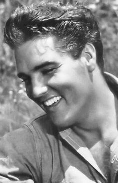 an old photo of a young man smiling and holding a bird in his hand,