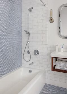 a bathroom with a sink, mirror and bathtub next to a shower head mounted on the wall