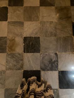 a black and white checkered bathroom floor with towels on the ground next to it