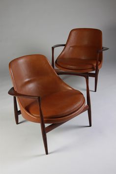 two brown leather chairs sitting next to each other on top of a white flooring