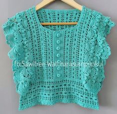 a green crocheted sweater hanging on a wooden hanger