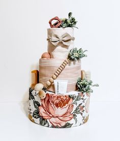 a three tiered cake made out of fabric with flowers and plants on the top