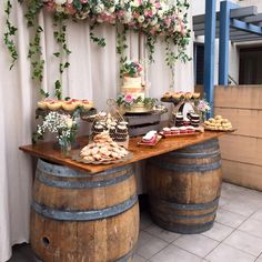 a table topped with lots of food next to barrels filled with cakes and pastries