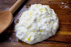 a wooden spoon sitting on top of a table next to a bowl of whipped cream