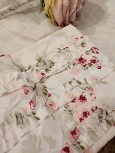 two folded sheets with flowers on them sitting on a bed next to a pillow case