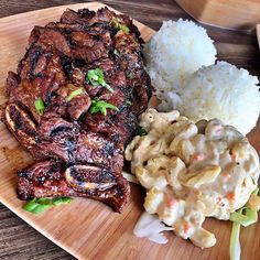 a wooden plate topped with meat, rice and cole slaw