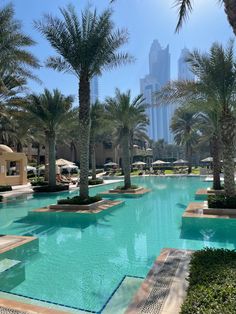 an empty swimming pool surrounded by palm trees and buildings in the backgrouds