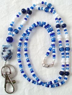 This blue & white beaded lanyard can be used as a badge holder, an I.D. holder, keychain necklace, watch holder - it's a multi-use accessory for home or office! 34" in length, long enough to put on or remove overhead. It also has an easy-to-use metal lobster clasp so you have a choice. It's made with glass beads and strung on strong (durable C-Lon beading cord. Snap-on badge holder, clip, and keyring are included to keep your badges or keys ready when you need them. This blue & white beaded lany Adjustable Beaded Blue Lanyards, Adjustable Blue Beaded Lanyards, Blue Beaded Jewelry For Everyday Use, Everyday Blue Beaded Jewelry, Blue Round Beads Jewelry For Everyday, Handmade Blue Lanyards For Gifts, Handmade Blue Lanyard As Gift, Handmade Blue Lanyards As Gifts, Blue Lanyard With Key Leash As Gift