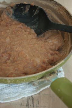 a spoon in a pot filled with food on top of a table