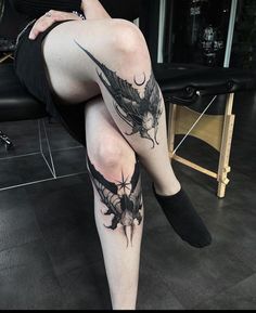 a woman sitting on top of a chair with her legs crossed and tattoos on the leg