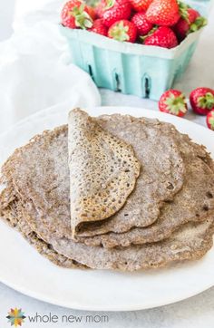 a stack of pita bread sitting on top of a white plate next to strawberries