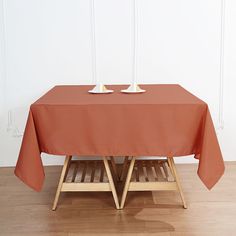 two white bowls sit on top of an orange tablecloth over a wooden bench in front of a white wall