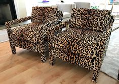 two leopard print chairs sitting on top of a hard wood floor next to a fireplace