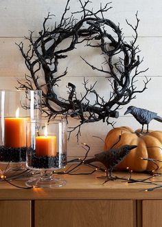 some candles are sitting on a table with branches and pumpkins in front of it