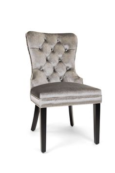 an upholstered grey velvet chair with buttons on the back and black wood legs