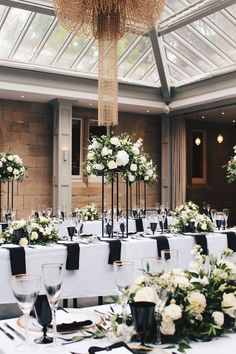 the tables are set with white flowers and black napkins for an elegant wedding reception