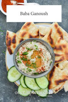 cucumber and pita chips with hummus on a plate next to dipping sauce