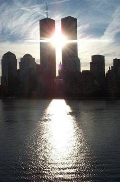 the sun shines brightly in front of some tall buildings on the water's edge