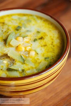 a yellow bowl filled with soup on top of a wooden table